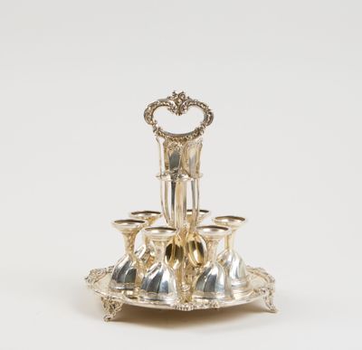 un plateau ancien en argent sur pied, sur lequel sont disposées quatre tasses
