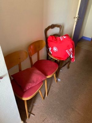 un sac rouge posé sur une chaise, à côté de deux autres chaises