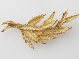 une image représentant une broche en feuille d'or posée sur une surface blanche
