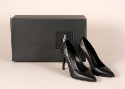 une paire de chaussures noires à talons hauts posée devant une boîte noire