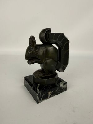 statue d'un écureuil posée sur un socle en marbre noir, sur fond blanc