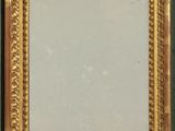 an image of a gold framed mirror on a green wall