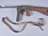 an old machine gun with a sling on a white surface