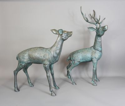 une paire de statues de cerfs en bronze sur fond blanc
