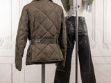 a coat and pants on a stand in front of a wall