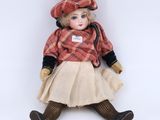 an image of a doll sitting on the ground wearing a dress and hat