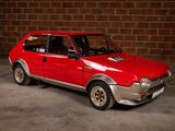 a red car that is parked in front of a brick wall