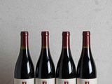 quatre bouteilles de vin rouge alignées sur une table en bois