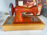 a red sewing machine sitting on a table next to a box