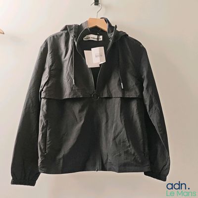 black leather jacket hanging on a hanger in a white room
