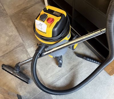un aspirateur jaune et noir posé par terre à côté d'un meuble noir
