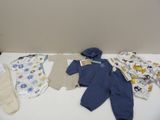 une table blanche sur laquelle sont posés des vêtements pour bébés et des moufles