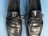 pair of black leather shoes with laces on them on a blue surface