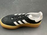 black and white adidas sneakers with gum soles on a gray surface