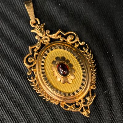 un gros plan d'une boucle d'oreille en or sertie d'une pierre rouge