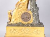 une horloge en or sur laquelle sont représentés une femme et un chien