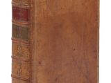 un vieux livre brun posé sur une surface blanche