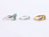 three gold and silver rings with green stones on them