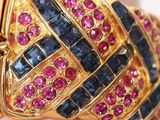 an image of a close up of a gold ring with blue, pink and red stones