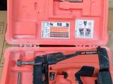 une mallette à outils rouge contenant un marteau et une cloueuse