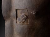 sculpture of a man ' s torso on a pedestal with a black background