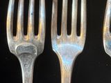 trois fourchettes sont posées les unes à côté des autres sur une surface noire