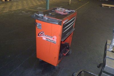 un chariot à outils orange contenant des outils, dans un entrepôt