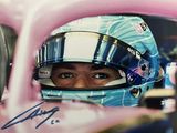 une voiture de course rose avec un homme casqué assis au volant