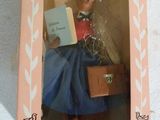barbie doll in a box holding a piece of paper with writing on it