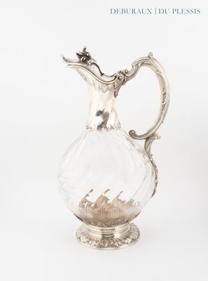un pichet en verre rempli de sable posé sur une surface blanche