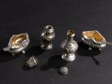 five silver vases sitting on a black surface next to each other