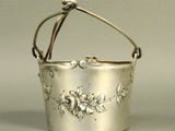 an antique silver metal bucket with flowers and vines on it