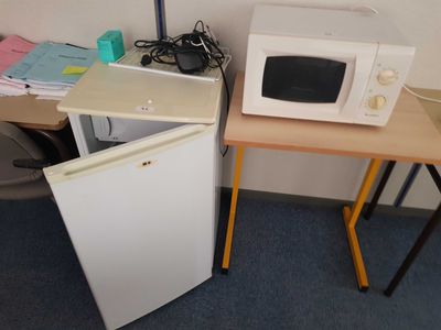 two microwaves sitting on a small table next to each other