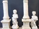 trois statues blanches d'enfants assis au sommet d'un pilier de pierre