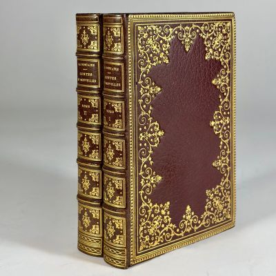 an old book with gold trimming and a red cover