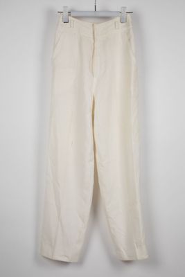un pantalon blanc suspendu à un cintre contre un mur