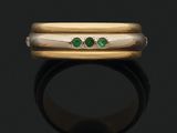 un gros plan d'une bague en or sertie de deux émeraudes
