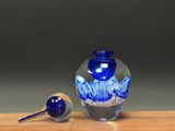 a blue glass vase and a glass spoon sitting on a table