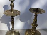 pair of antique brass candlesticks on display in front of a white wall