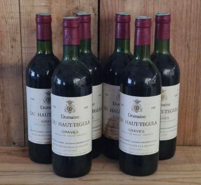 four bottles of wine are lined up on a wooden shelf