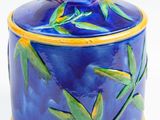 a blue and yellow container with bamboo handles on a white surface