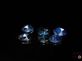 quatre saphirs bleus sur une surface noire dans l'obscurité