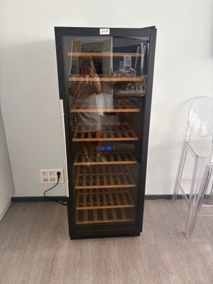 someone taking a picture of a wine cooler in a room