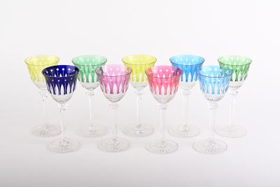 six different colored wine glasses lined up in a row on a white surface
