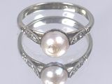 deux bagues ornées de perles et de diamants, posées sur un fond blanc
