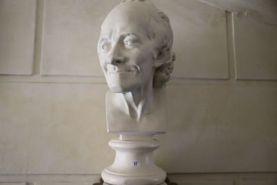 un buste d'homme posé sur un socle dans une pièce