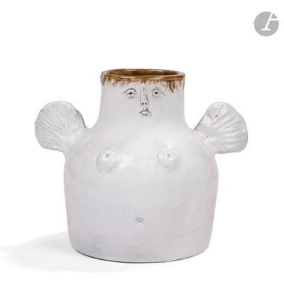 un vase blanc orné d'un visage, posé sur une surface blanche