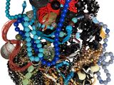 un tas de perles et de colliers de toutes sortes posés sur une surface blanche