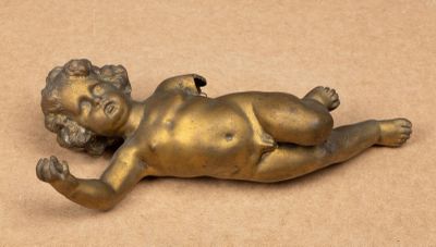 statue en laiton représentant un bébé allongé sur le dos sur une surface marron