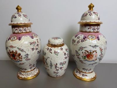 two vases with lids are sitting on a table in front of a wall